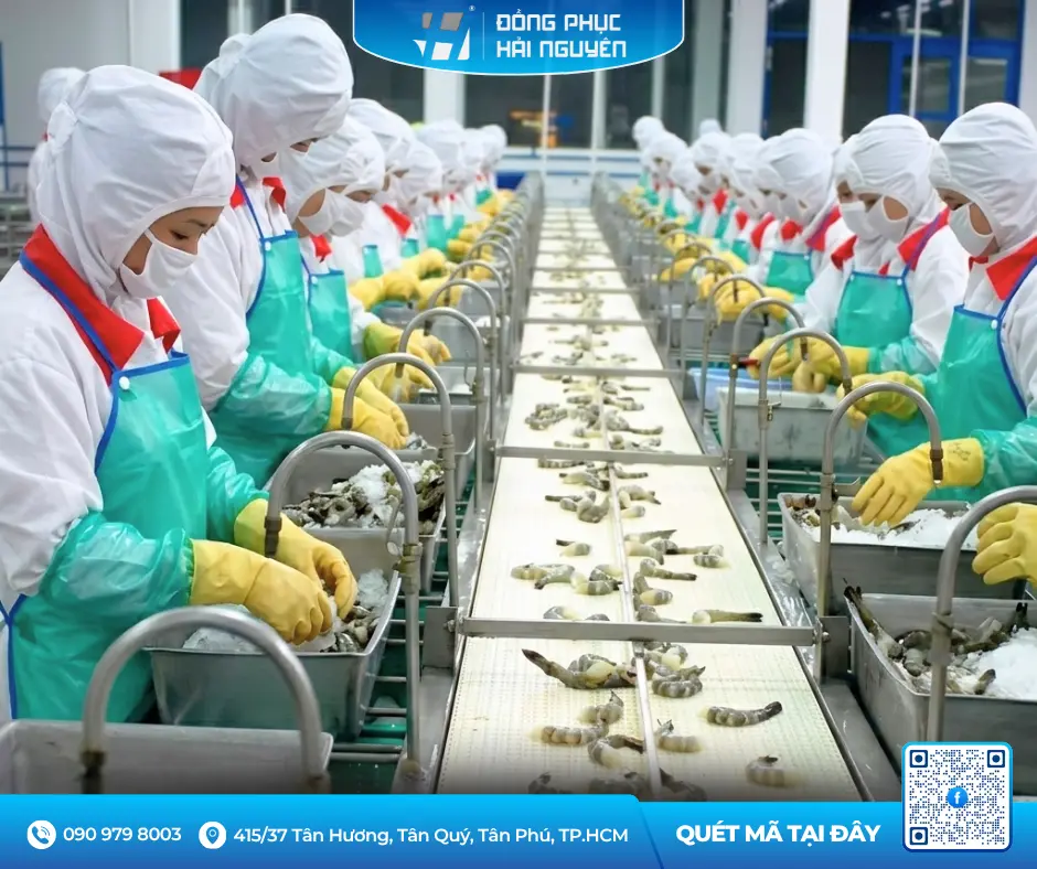 Nhân viên sơ chế thực phẩm đeo tạp dề nhựa màu xanh chống thấm tại dây chuyền sản xuất nhà máy.